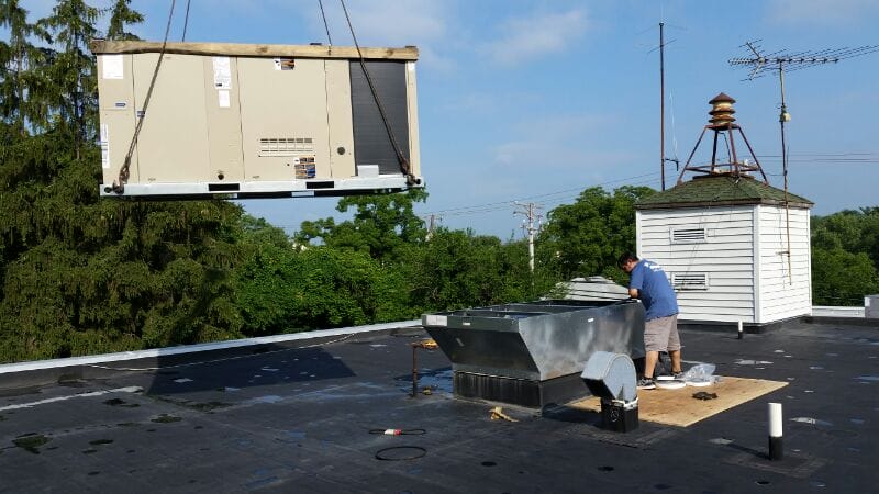 crane bringing large commercial hvac rooftop unit onto roof on industrial building in elkridge md